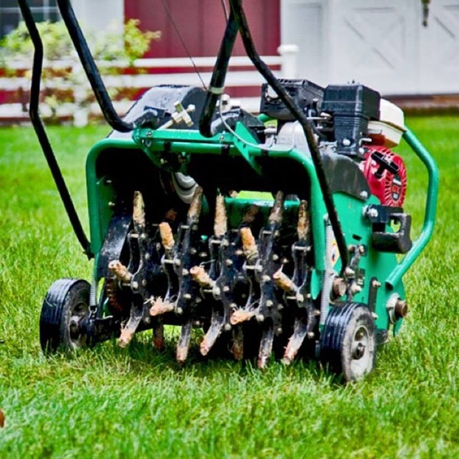 Core aerator with soil plugs packed in its hollow tines after coring a lawn
