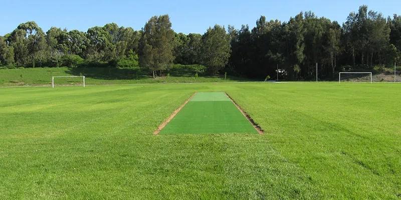 Freshly mown sports oval with a cricket wicket and soccer goals